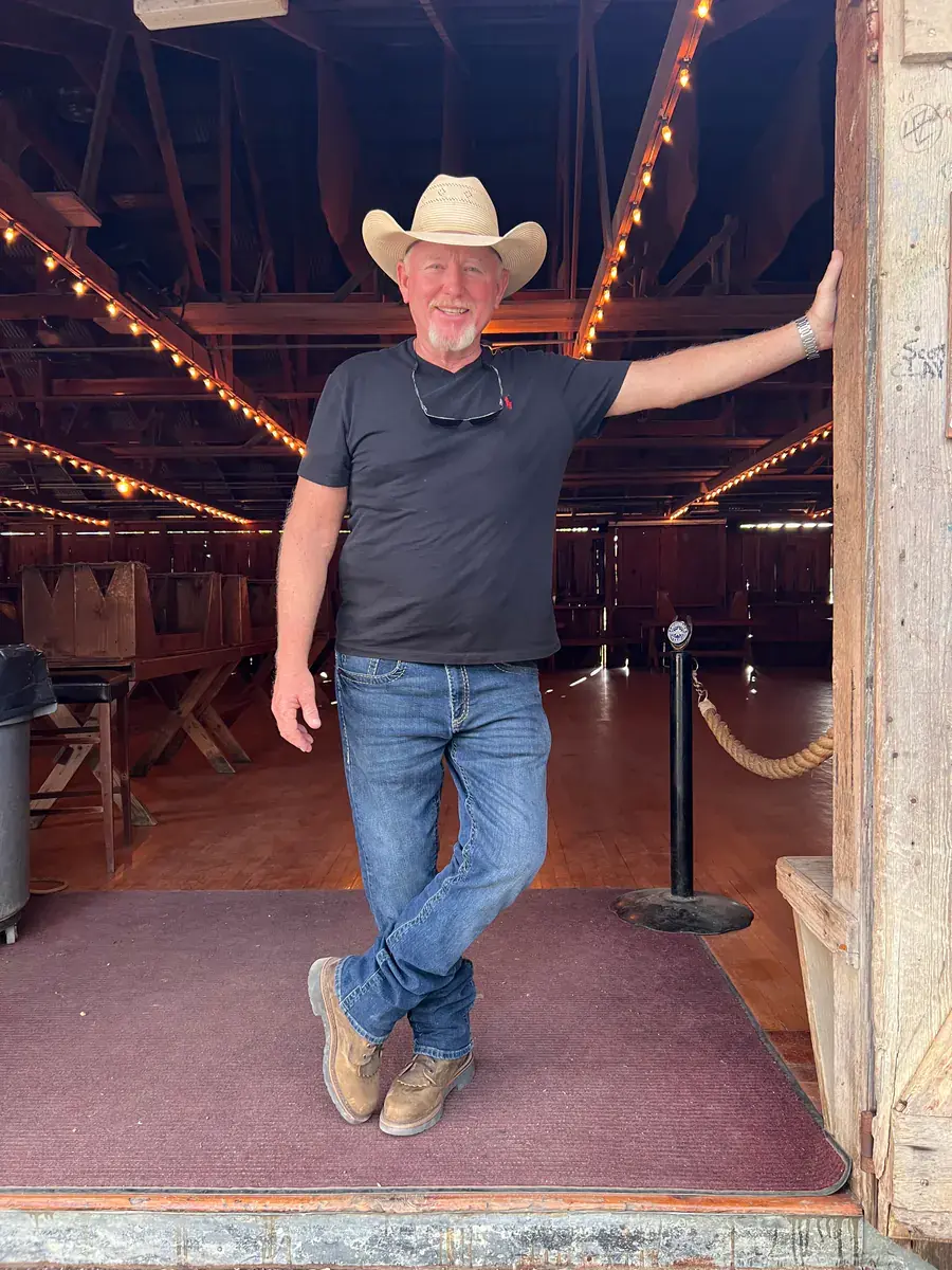 Virgil Klaus wearing a cowboy hat and standing in a rustic doorway